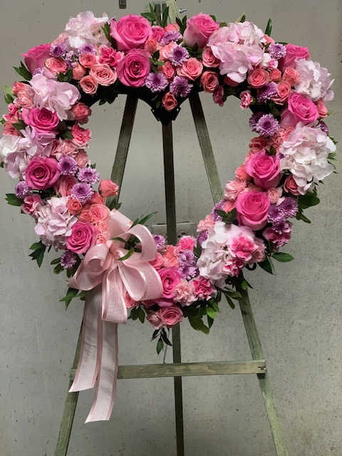 Heart-shaped floral wreath of pink roses and hydrangeas with a ribbon bow