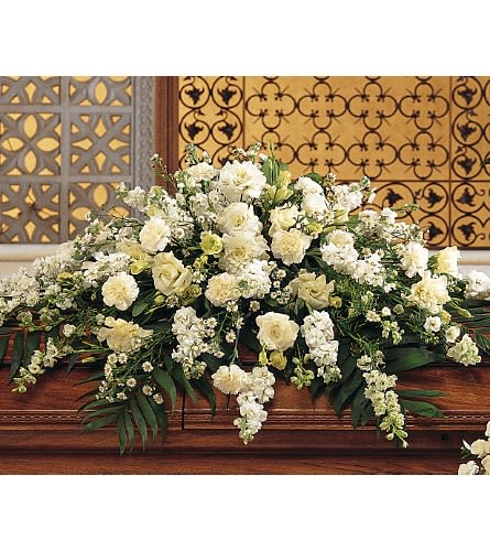 Large white floral arrangement on a wooden casket