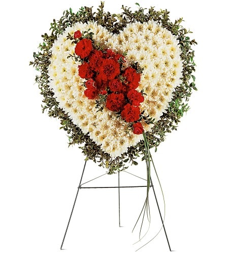 Heart-shaped funeral spray of white and red flowers on a stand