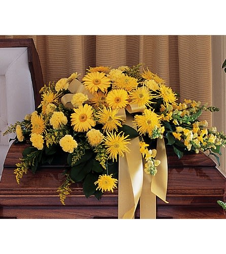 Yellow floral casket spray with ribbon on a wooden casket