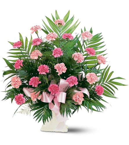 Pink carnations in a white vase with a pink ribbon