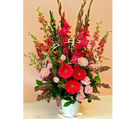 Tall red and pink flower arrangement in a white vase
