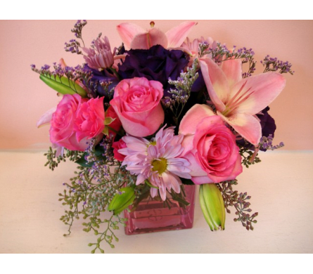 Pink roses and lilies arranged in a square glass vase