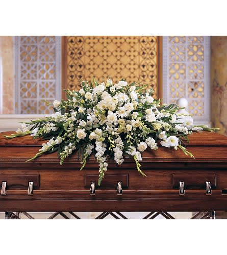 White floral casket spray on a wooden casket
