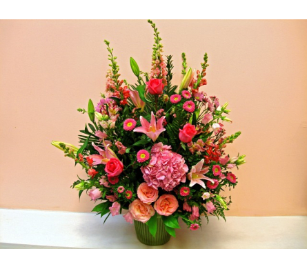 Pink and peach mixed flower arrangement in a green vase