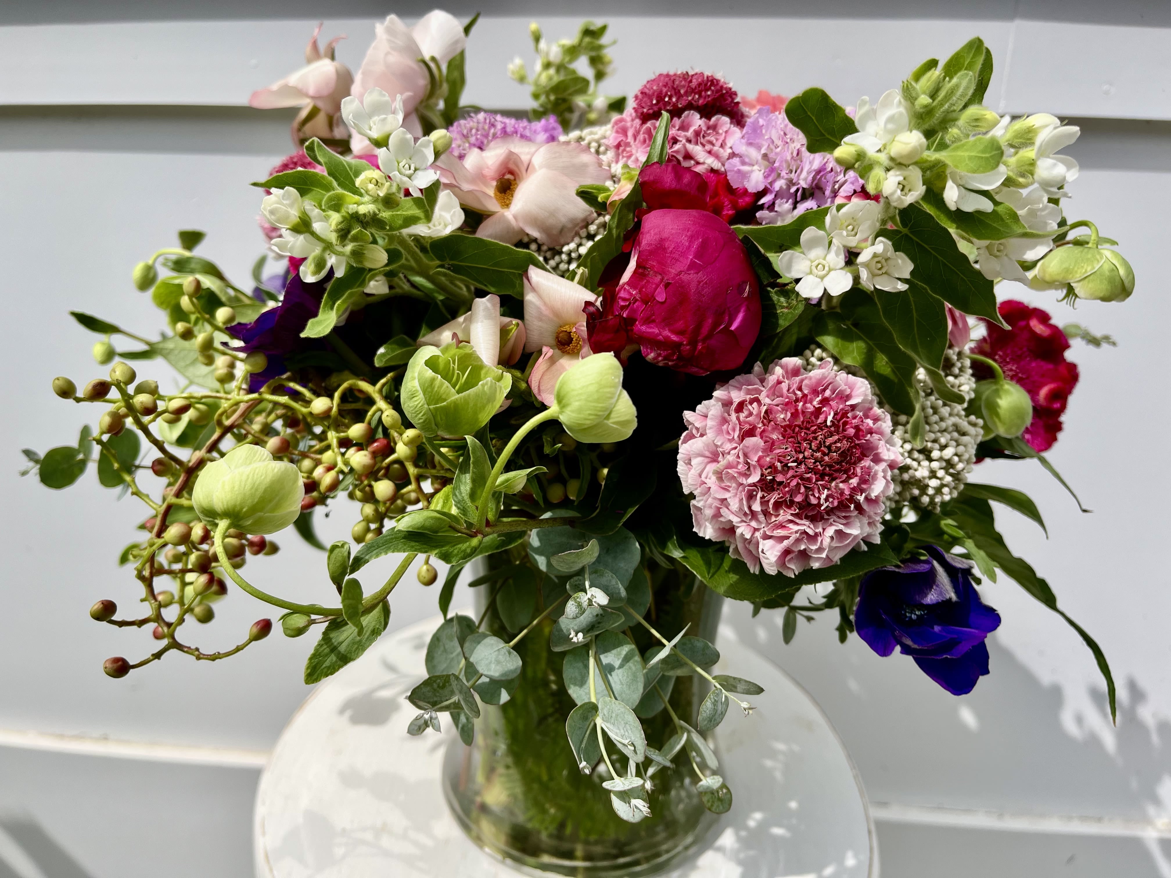 Spring Romance - Scabiosa, garden roses, tweedia, hellebores, anemone with eucalyptus in a clear glass vase.