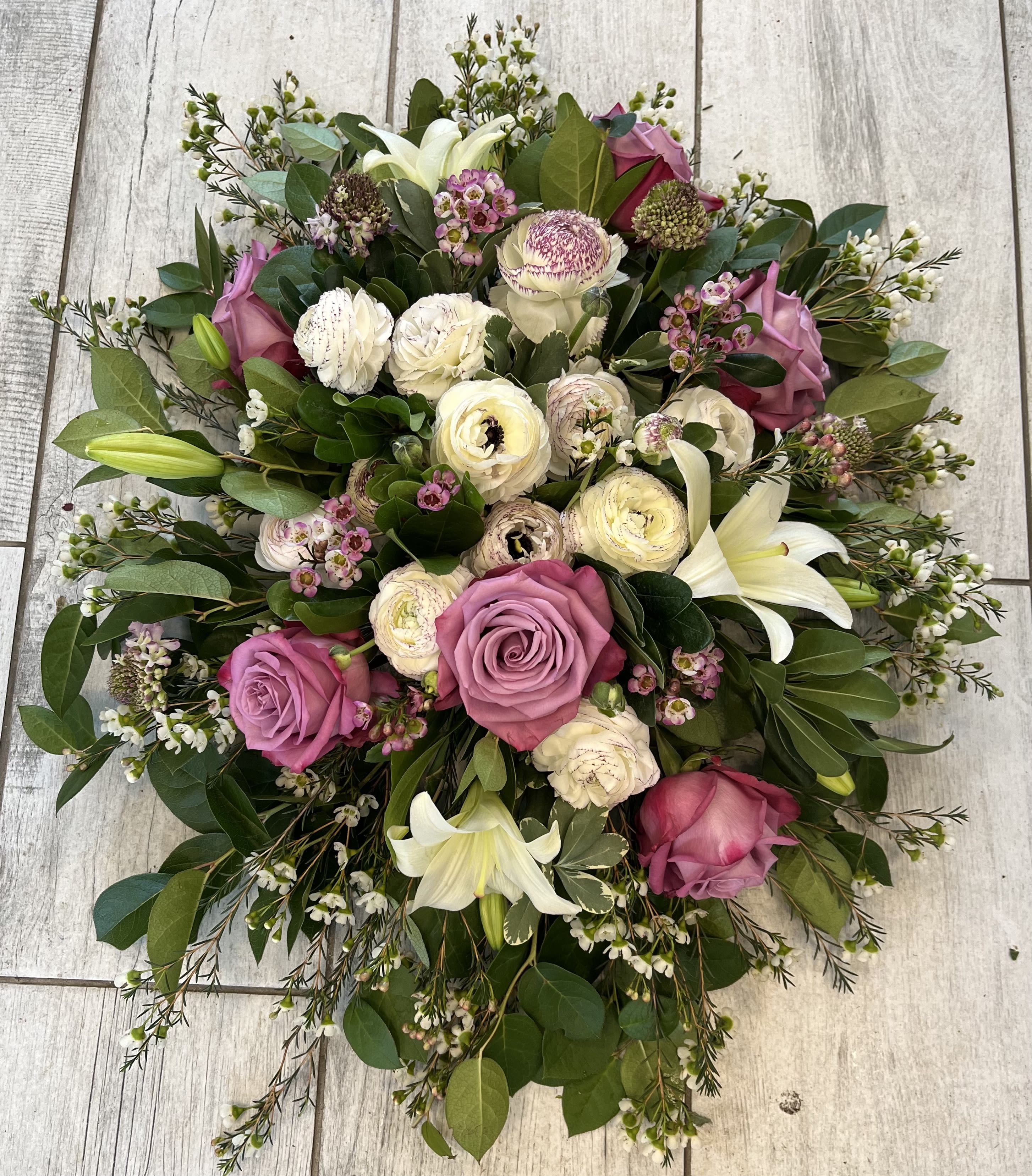 Tranquil Spray - Funeral spray with roses, ranunculus, waxflower, lilies, and scabiosa in shades of pink and raspberry. 