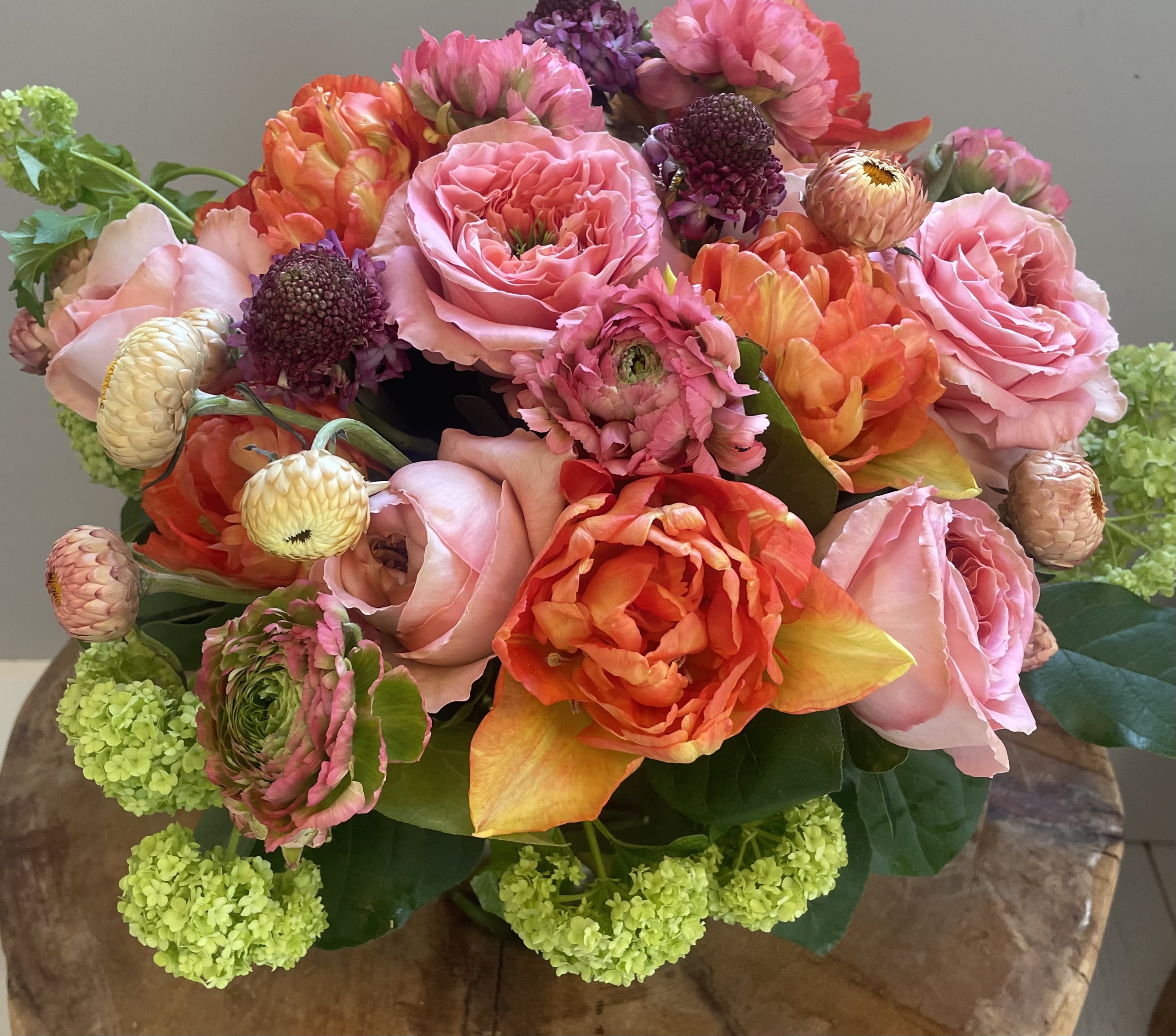 Shades of Coral - Roses, strawflower, hydrangea, tulips and scabiosa and ranunculus,in a vase in shades of peach coral and green.