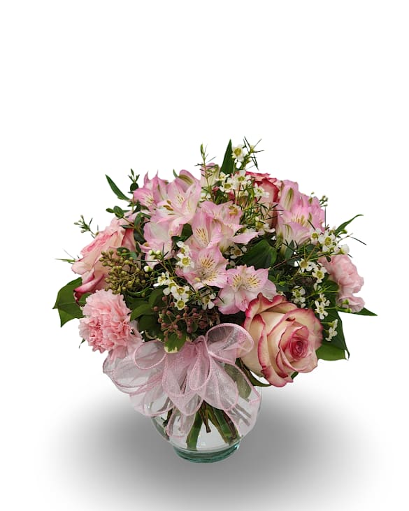 Pink mixed flower bouquet in a glass vase with a pink ribbon