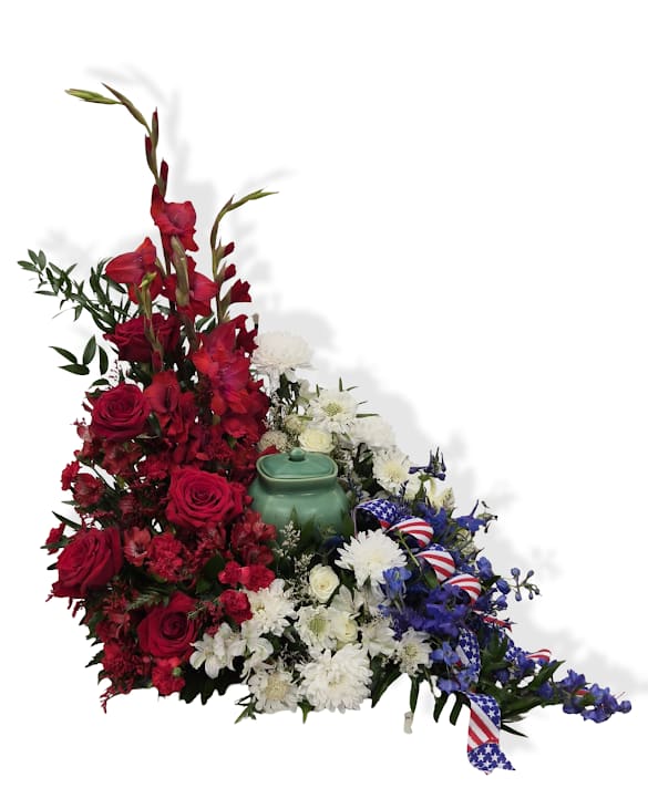Freedom's Tribute Cremation Adornment - Freedom's Tribute Cremation Adornment is a red, white and blue arrangement designed to frame and honor an urn during services. Featuring roses, seasonal blooms, patriotic ribbon, and lush greenery.  Approx. 30" x 24"   *Urn not included. If you have the urn dimensions and shape. please include them in the special instructions so we can ensure the best fit.*
