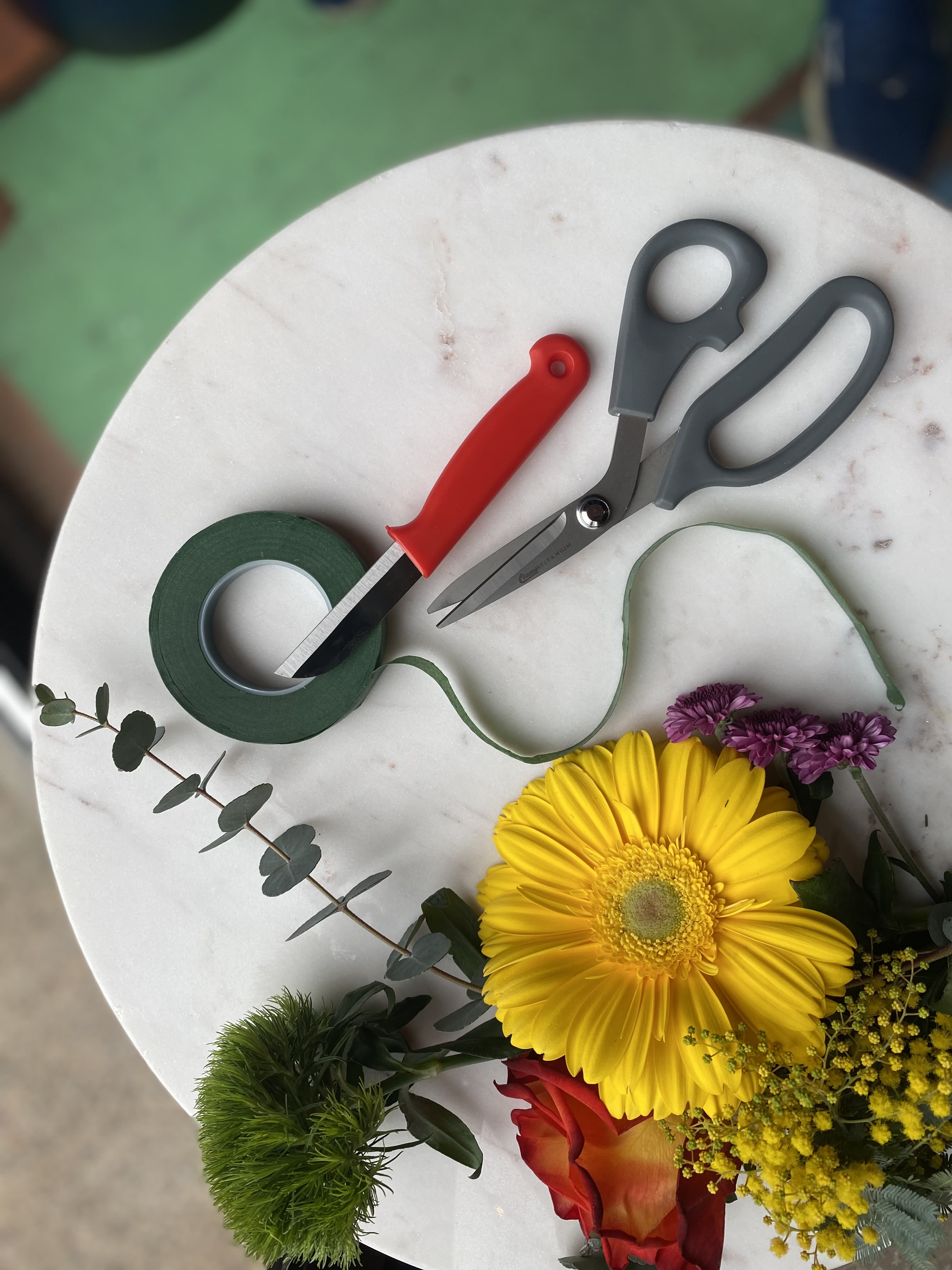 Floral arranging tools and a small bouquet with a yellow gerbera daisy
