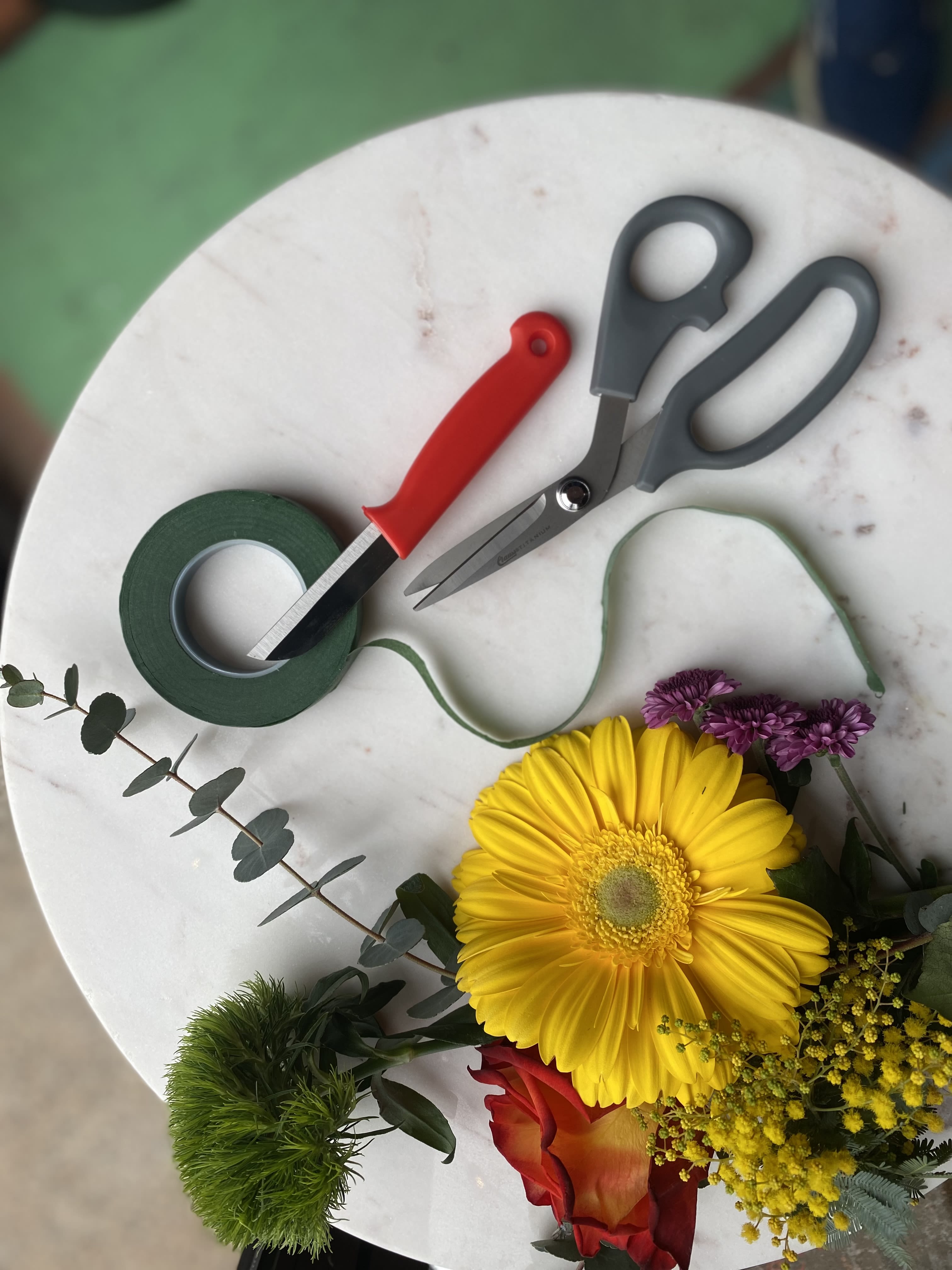 Floral tools and a small bouquet with a yellow gerbera daisy and red rose