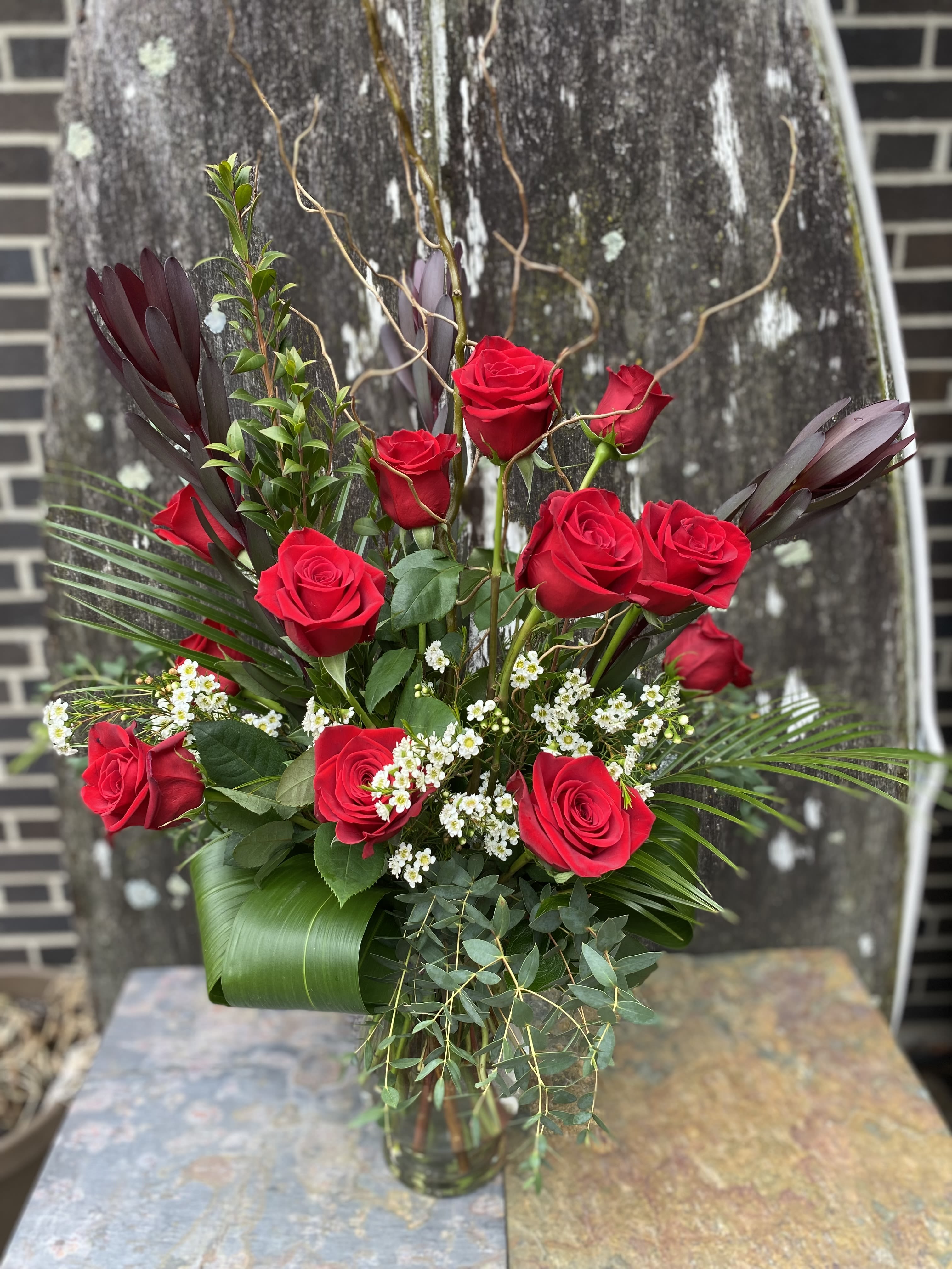 Red roses arranged in a glass vase with white filler flowers