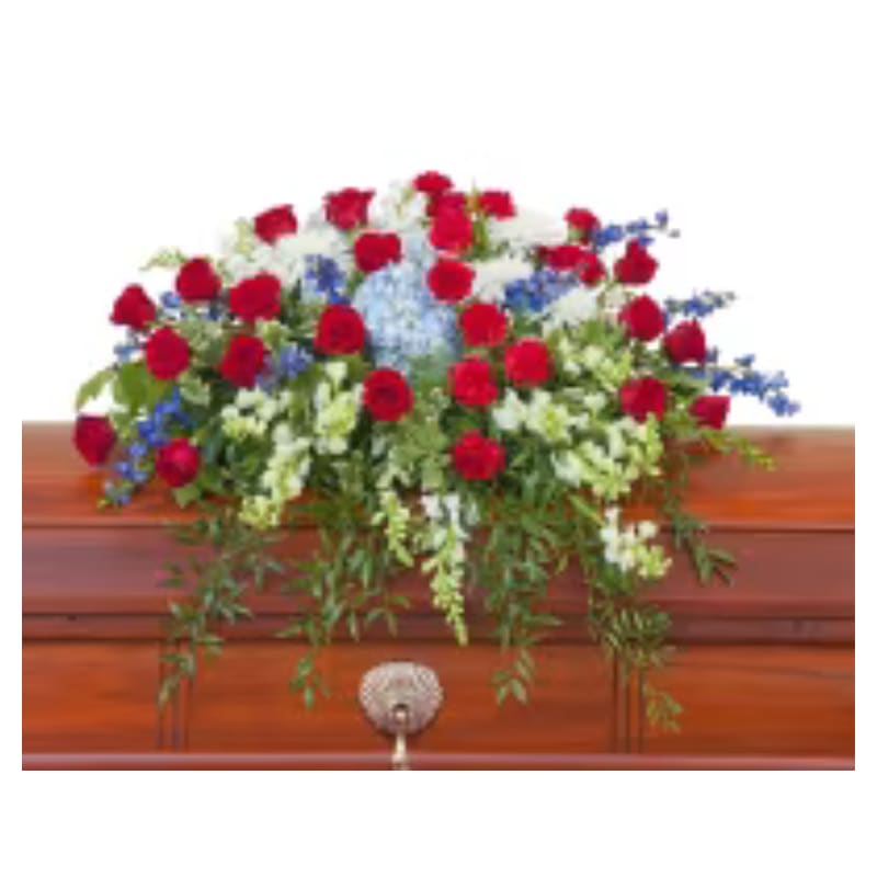Red roses and white flowers arranged on a wooden casket