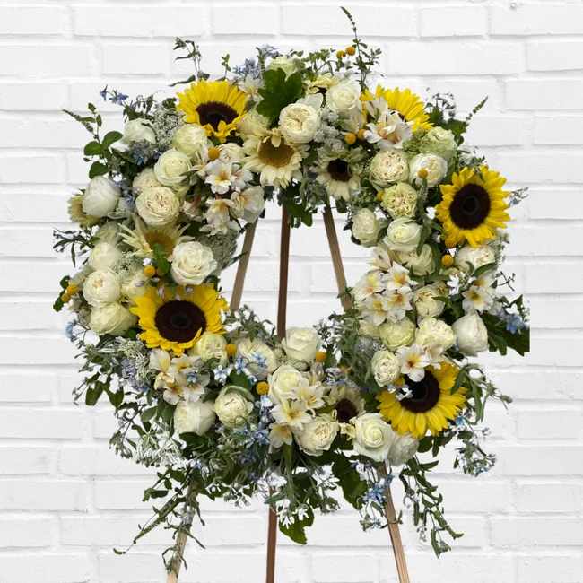 Large floral wreath with white roses and sunflowers on a stand