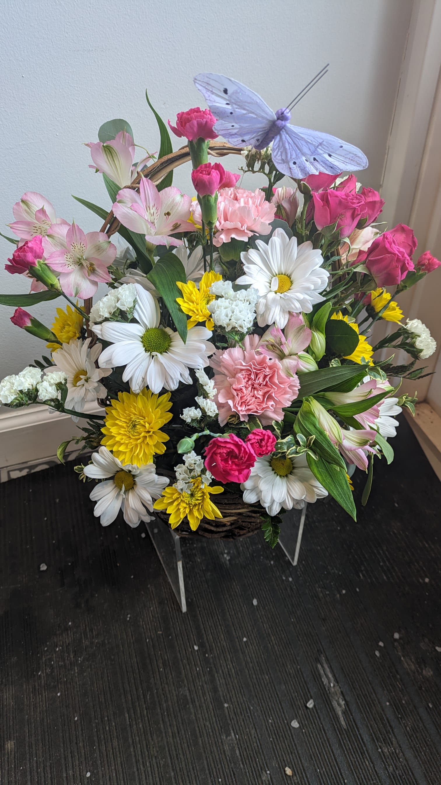 Mixed flower basket with daisies, carnations, roses, and a butterfly decoration