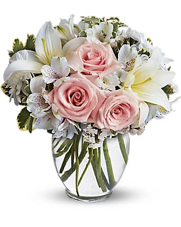 Pink roses and white lilies arranged in a clear glass vase