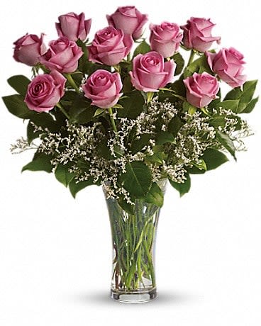 Pink roses arranged in a clear glass vase with white filler flowers