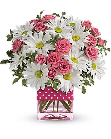 Pink roses and white daisies in a clear square vase with a polka-dot wrap