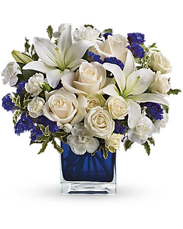White lilies and roses arranged in a blue glass vase