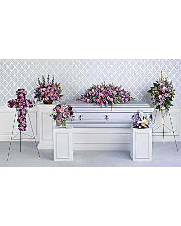 Funeral casket spray and standing floral tributes in pink and purple