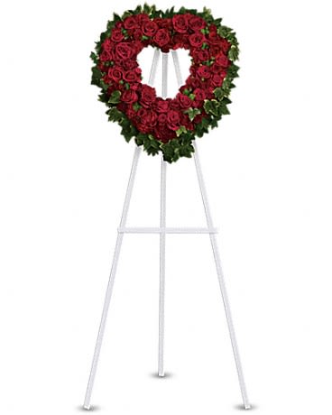 Heart-shaped standing wreath of red roses on a white easel