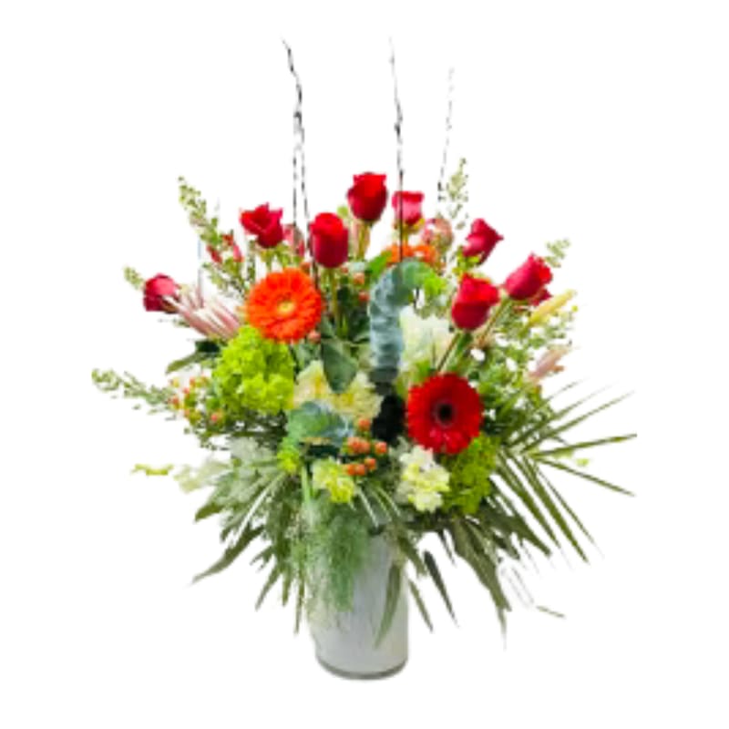 Mixed bouquet of red roses and bright gerbera daisies in a white vase