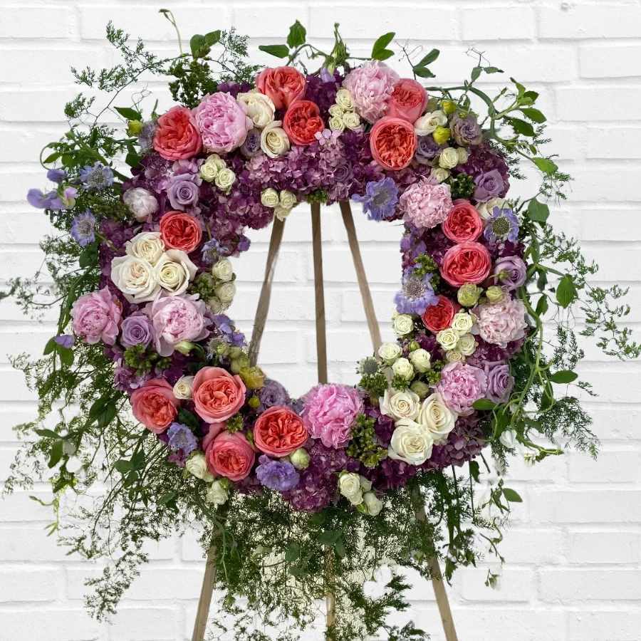 Spring Funeral Wreath - This 24" funeral wreath embodies the colorful spirit, joyfulness, and femininity of your loved one. It is the perfect tribute for your best friend, mother, or anyone who radiated positivity and happiness. It serves as a source of motivation and a reminder of the strong support system your loved one built. This wreath is a heartfelt expression of condolence.  Oregon: peonies. Ecuadorian: roses and spray roses. Colombian: hydrangeas. California-grown: scabiosa, sweet peas, asparagus fern.  Measures approximately 24" x 6ft. tall on an easel.