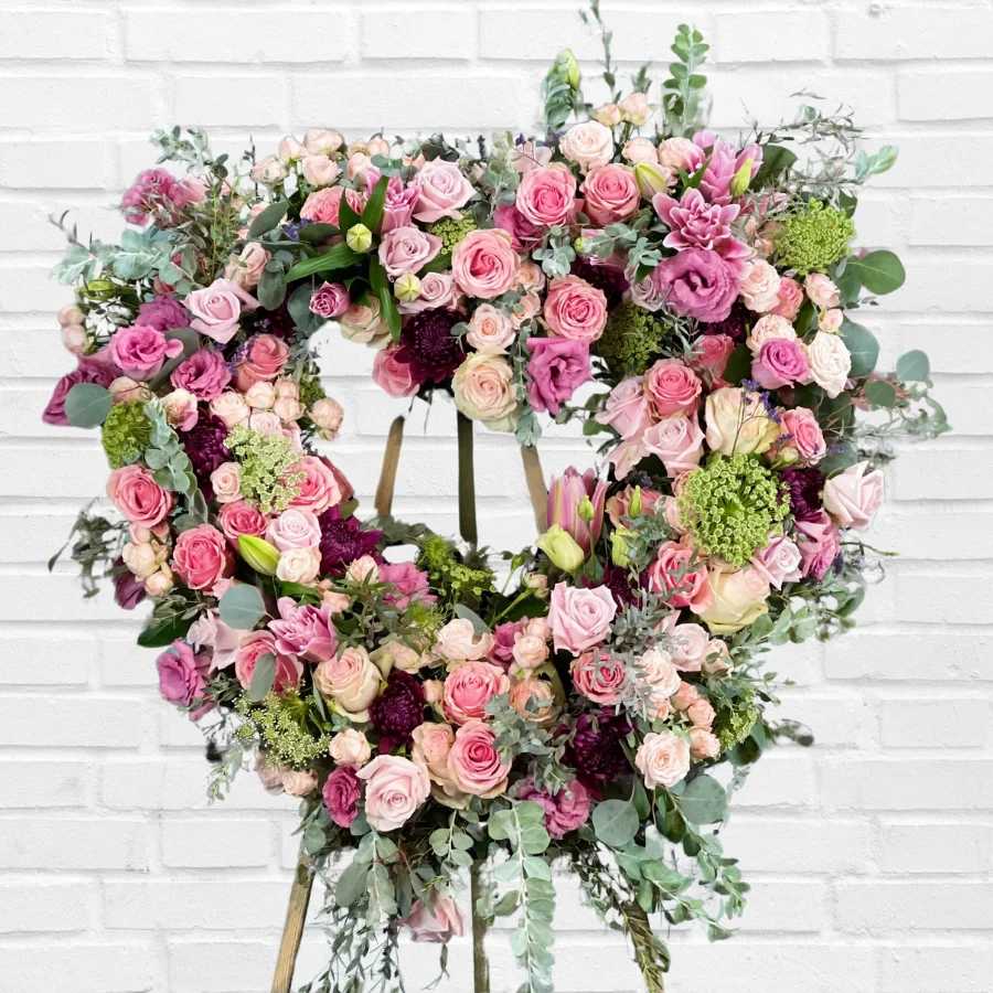 Heart-shaped floral wreath with pink roses and mixed blooms