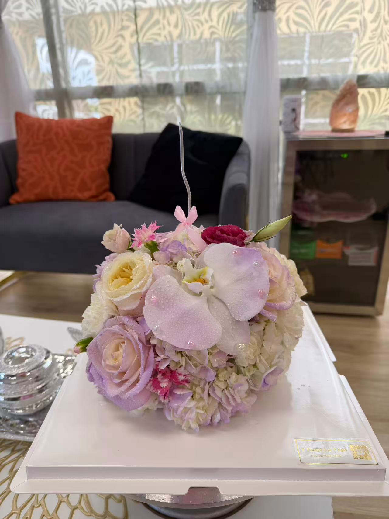 Round pastel bouquet with roses, orchids, and hydrangeas on a white box