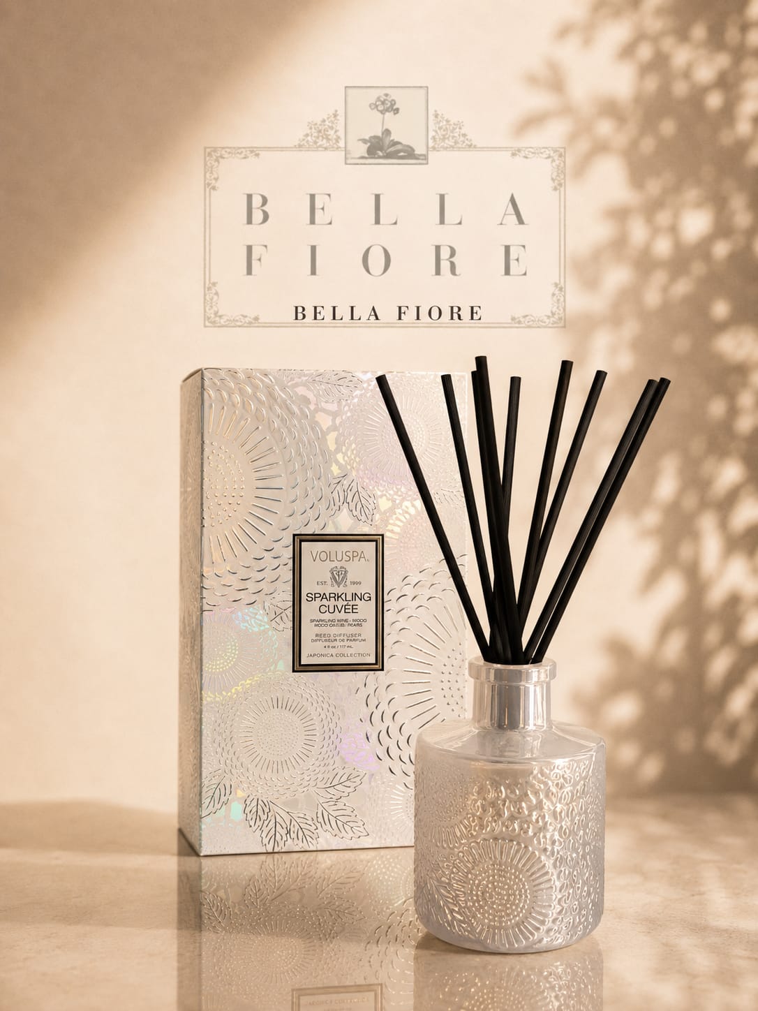A reed diffuser in a patterned glass bottle with a matching box