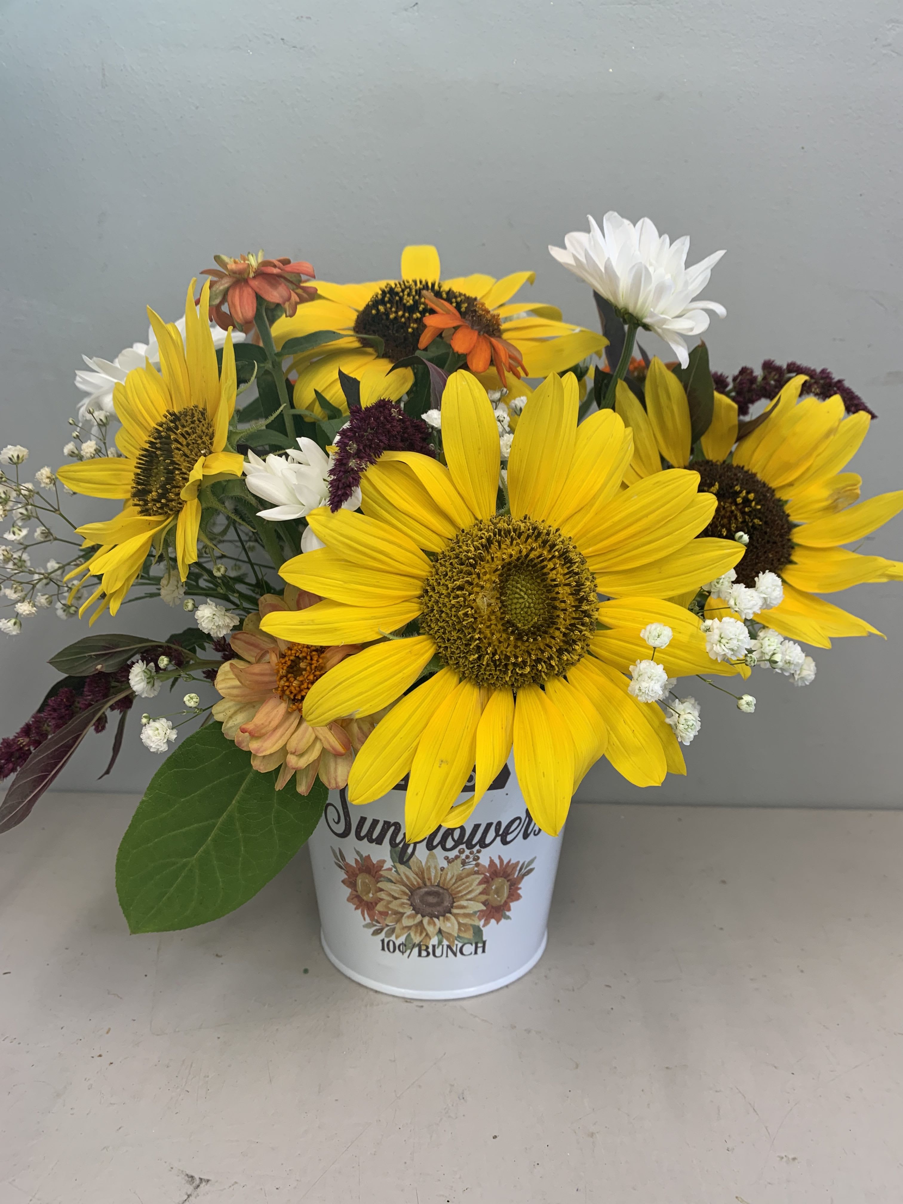 Sunflower bouquet in a white tin container with mixed accent flowers