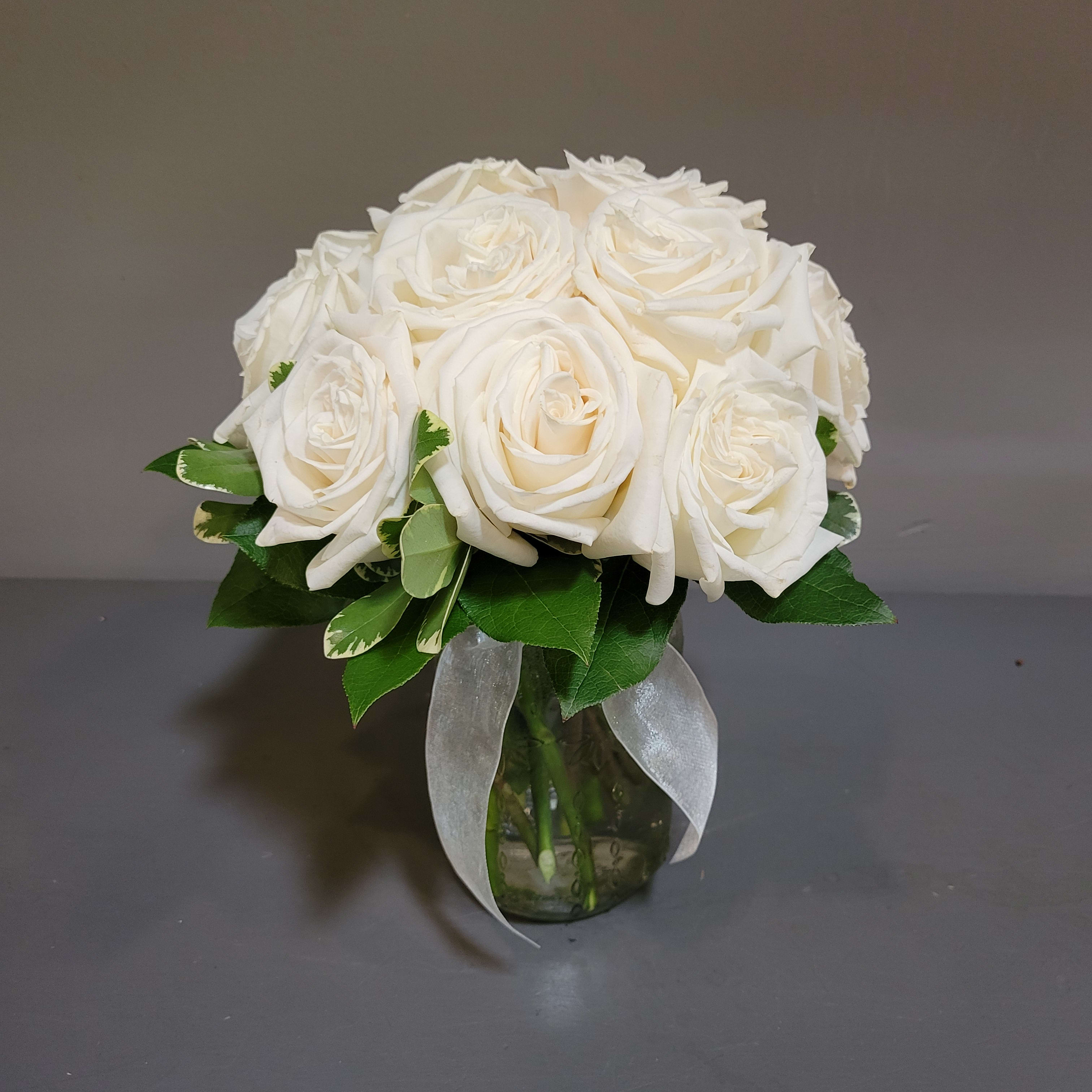 White rose bouquet in a glass vase with a sheer ribbon