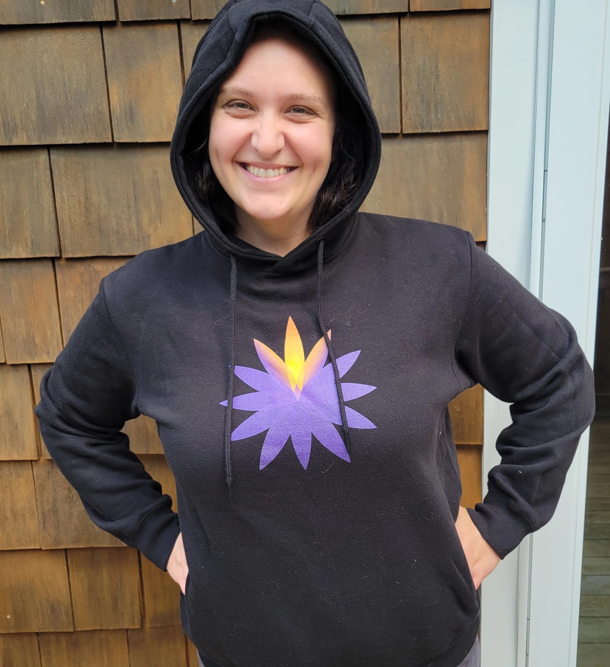 Person wearing a black hoodie with a purple and yellow flower graphic