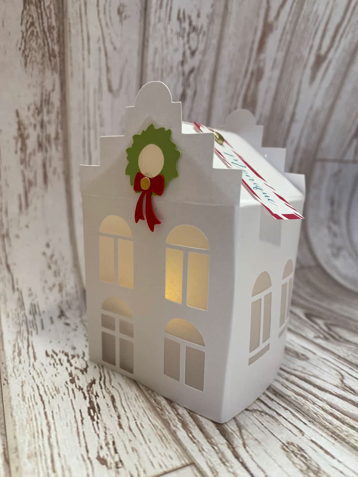 White paper house-shaped gift box with a holiday wreath decoration