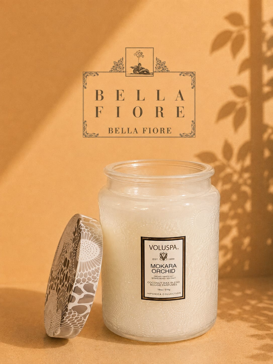 A white scented candle in a glass jar with a patterned lid
