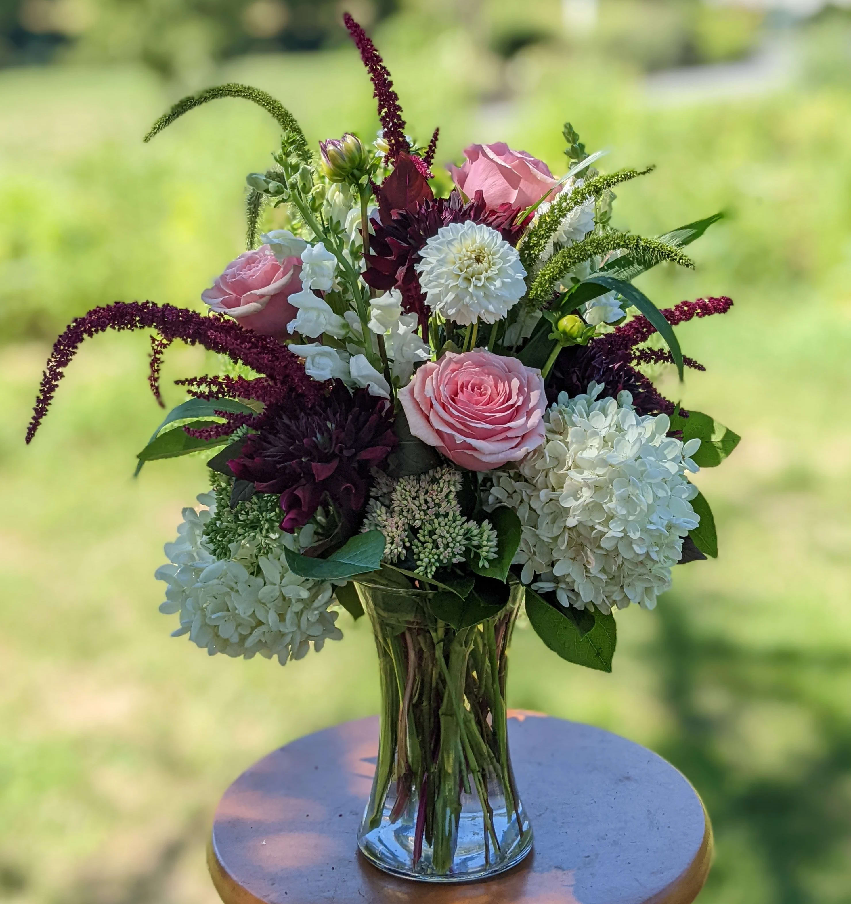 Pink roses and white blooms arranged in a clear glass vase