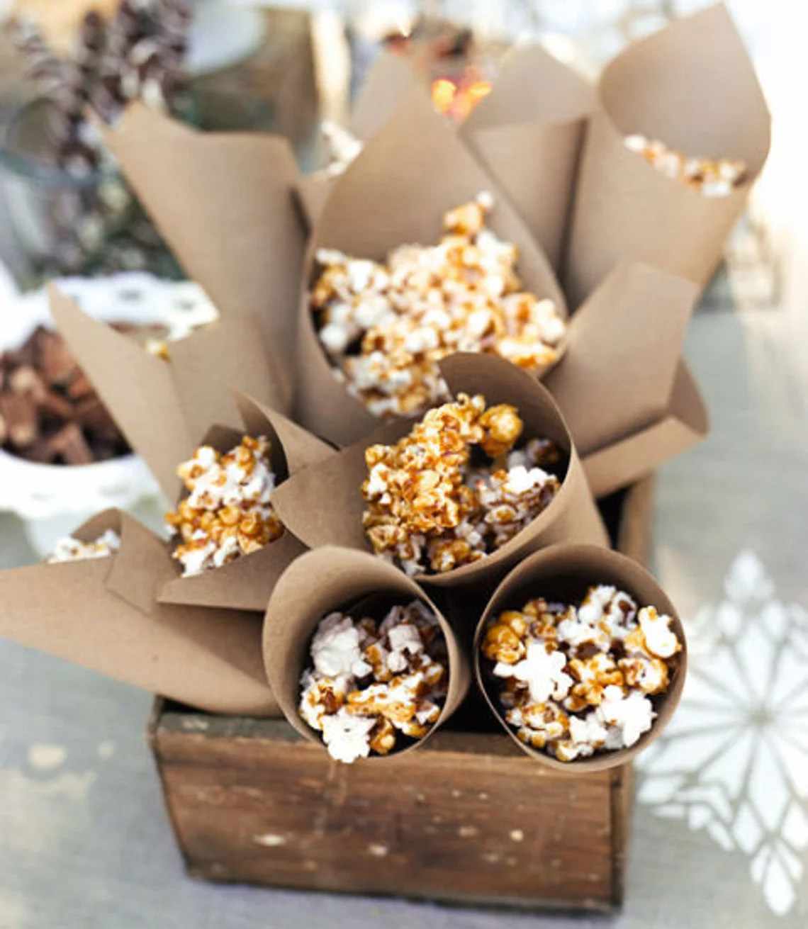 Paper cones of caramel popcorn arranged in a wooden crate