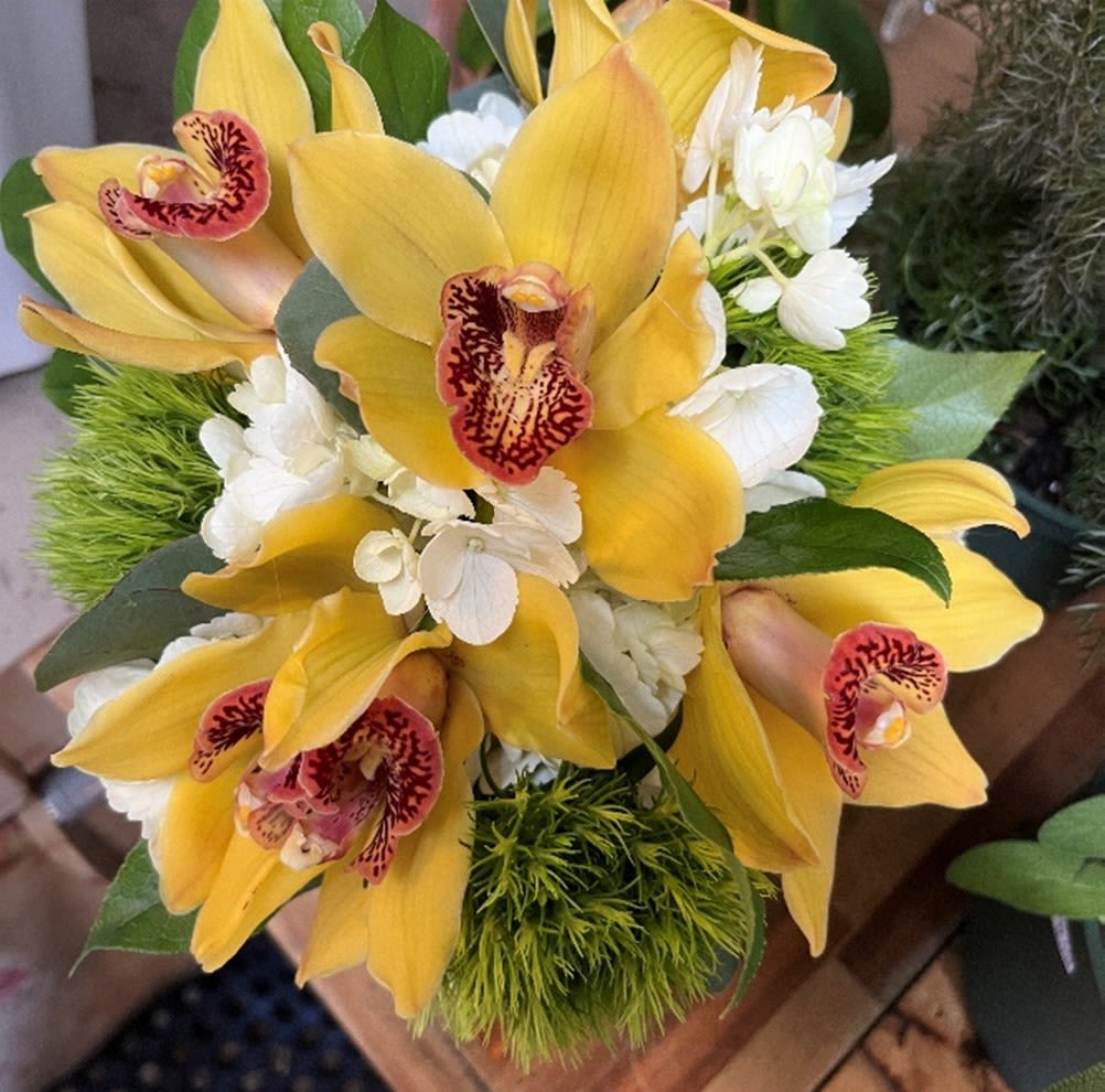 Bouquet of yellow orchids with white flowers and green accents