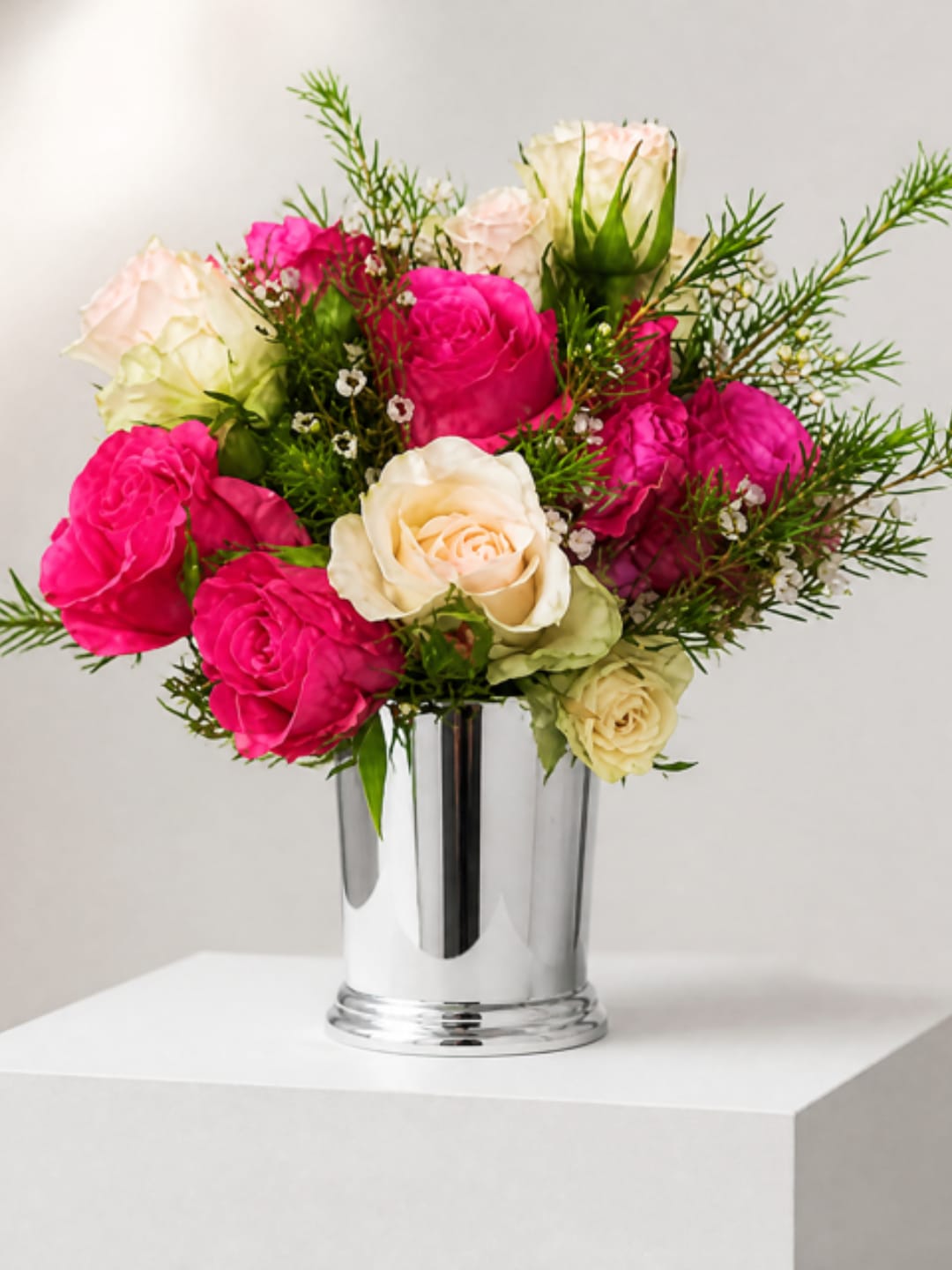 Pink and cream roses arranged in a silver vase