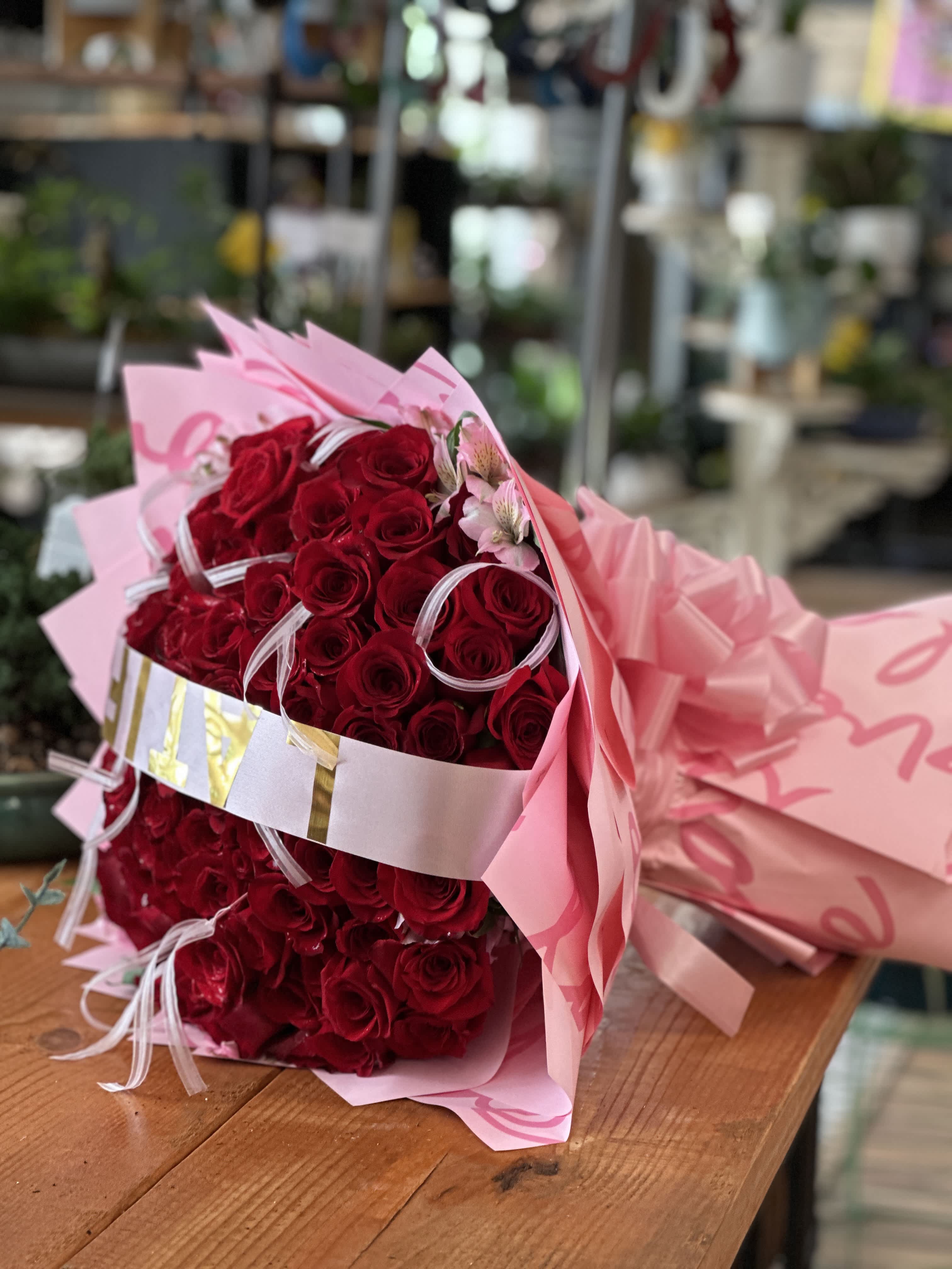 Bouquet of red roses wrapped in pink paper with ribbon