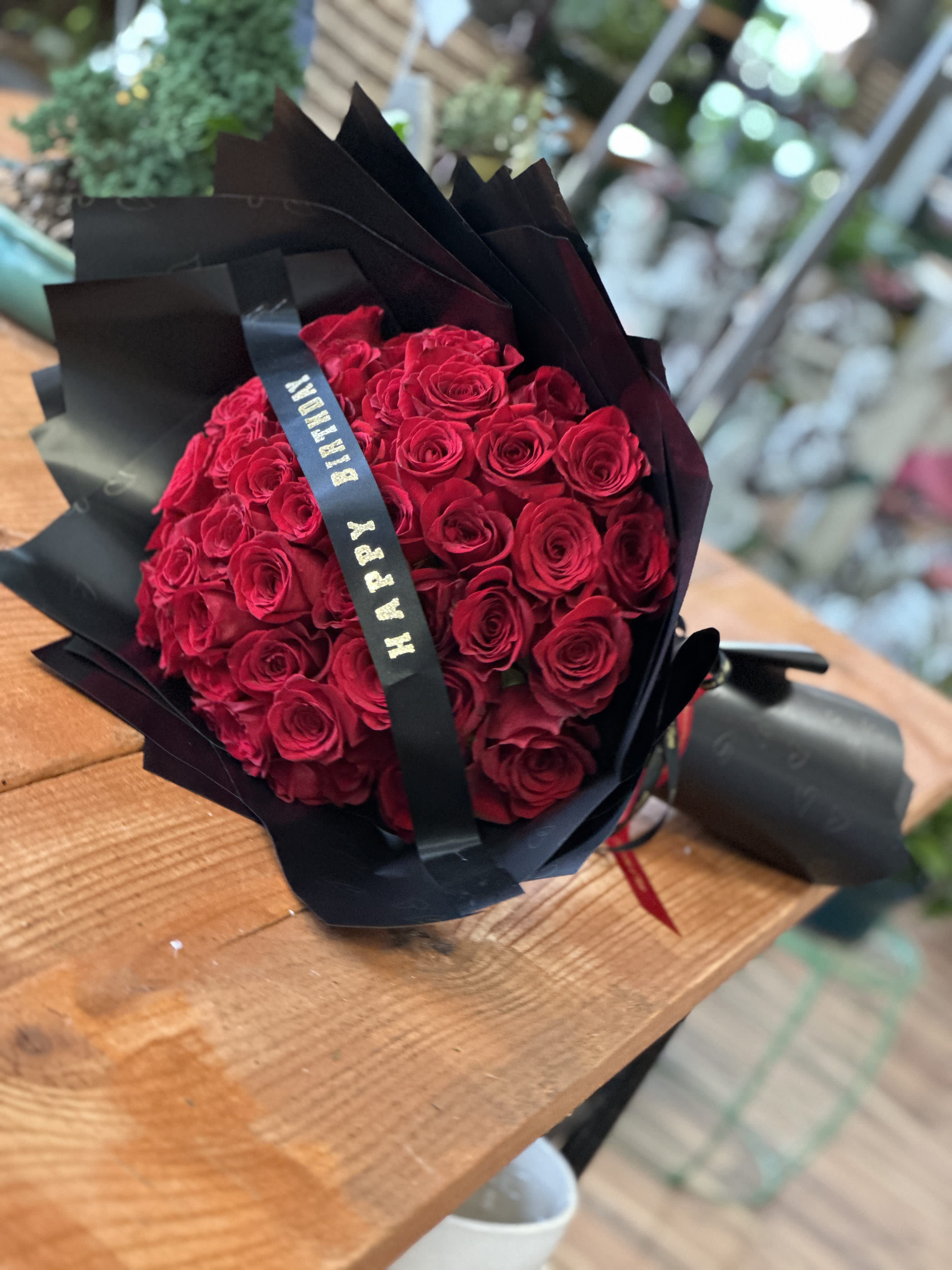 Bouquet of red roses wrapped in black paper with a ribbon
