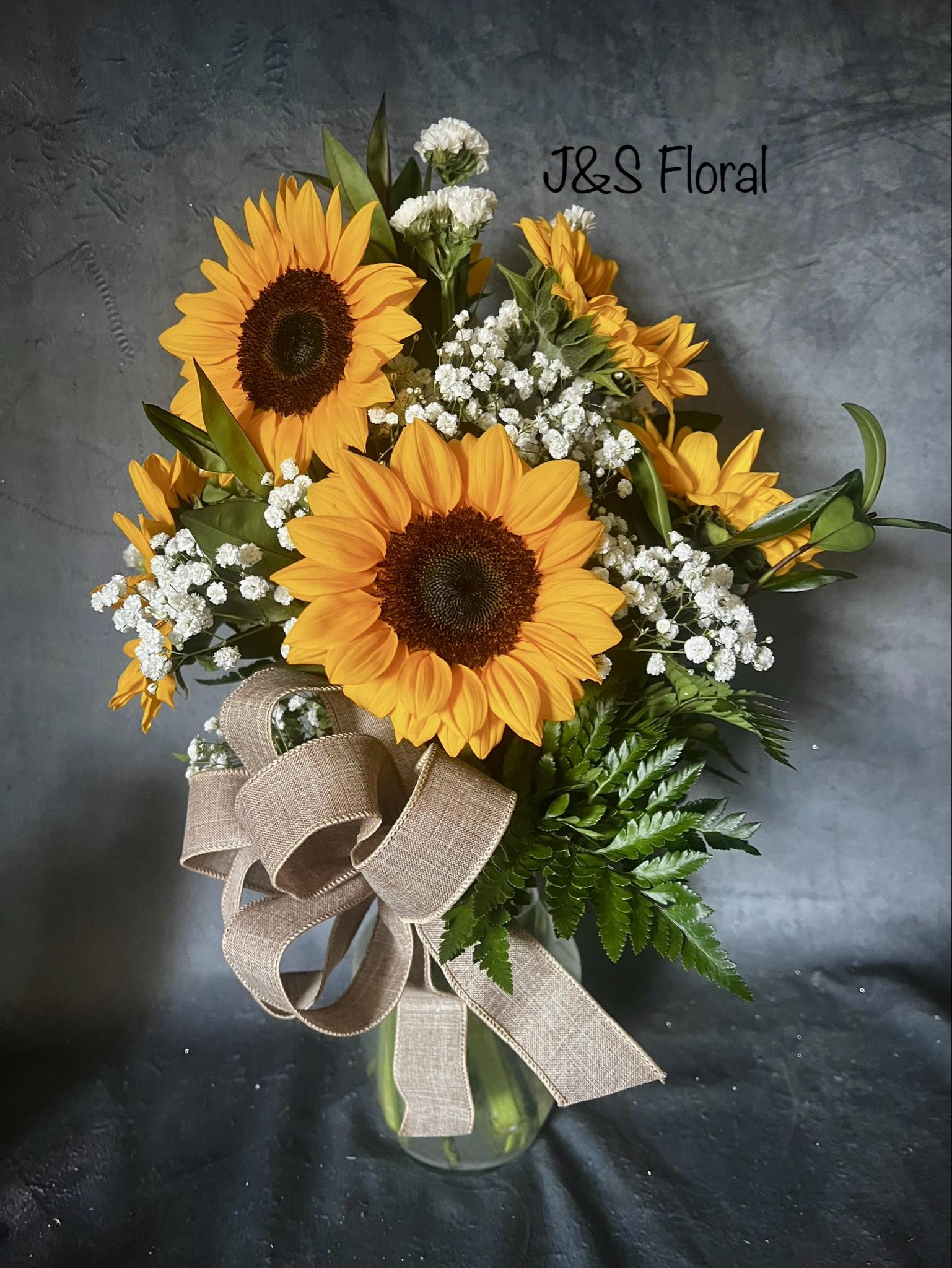 Sunflower bouquet in a glass vase with baby's breath and a burlap ribbon