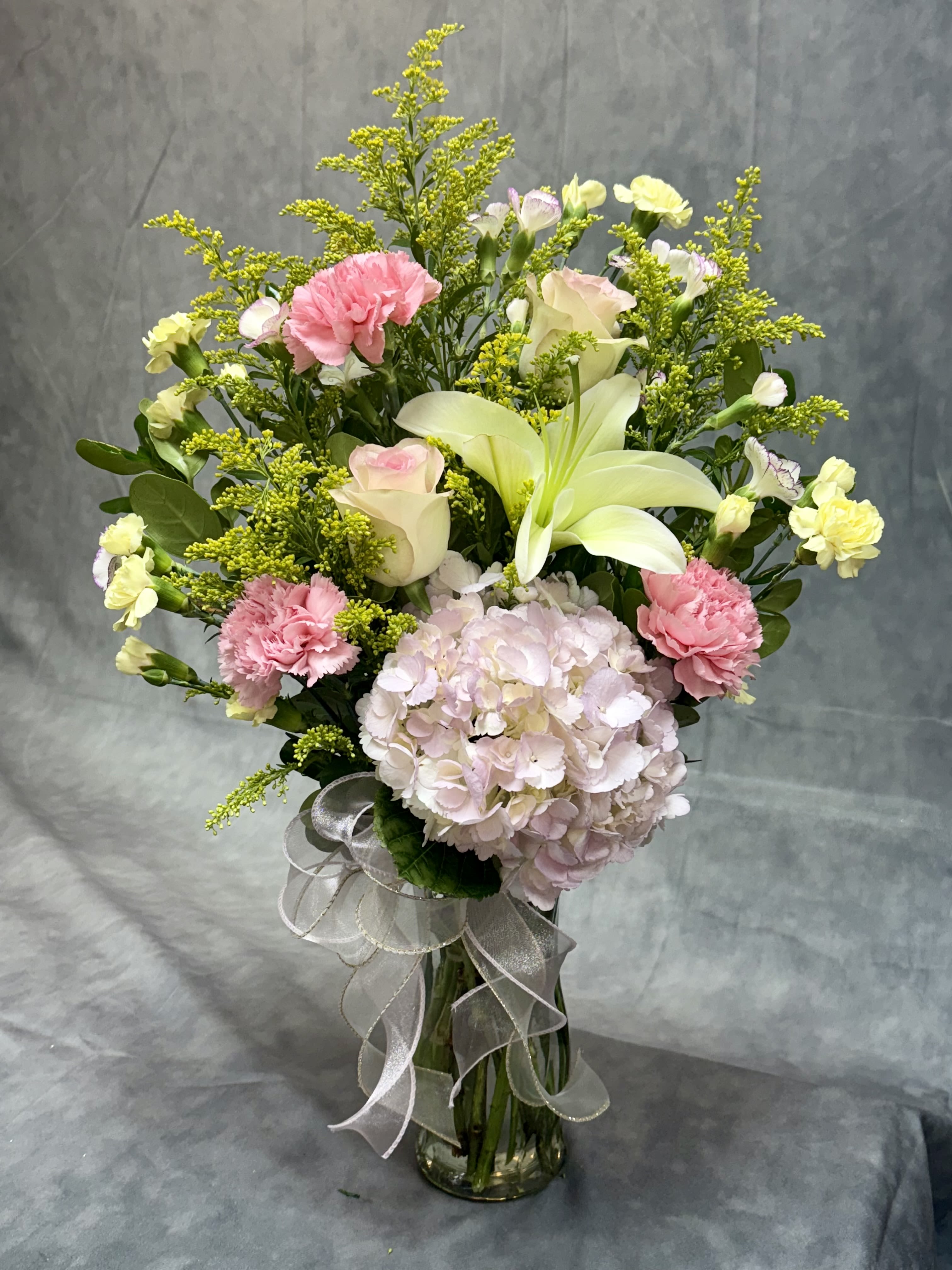 Bouquet of pink and white flowers in a glass vase with a ribbon