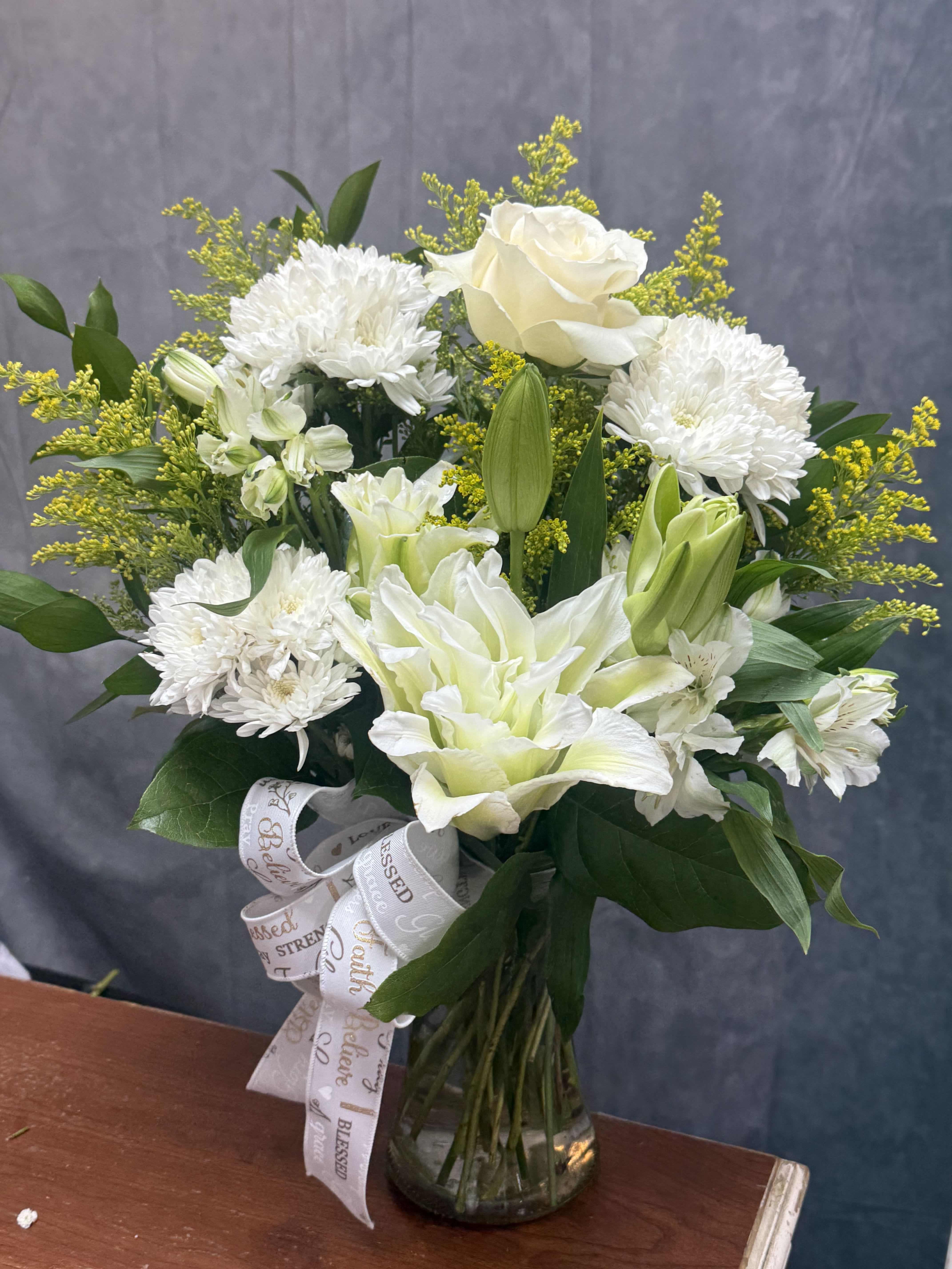 White Blooms Vase  - A timeless arrangement of elegant white lilies, roses, chrysanthemums, and alstroemeria, thoughtfully designed in a clear glass vase. The White Blooms Vase offers a beautiful expression of peace, comfort, and grace, making it a perfect gift for sympathy, remembrance, or any occasion that calls for a touch of elegance. 