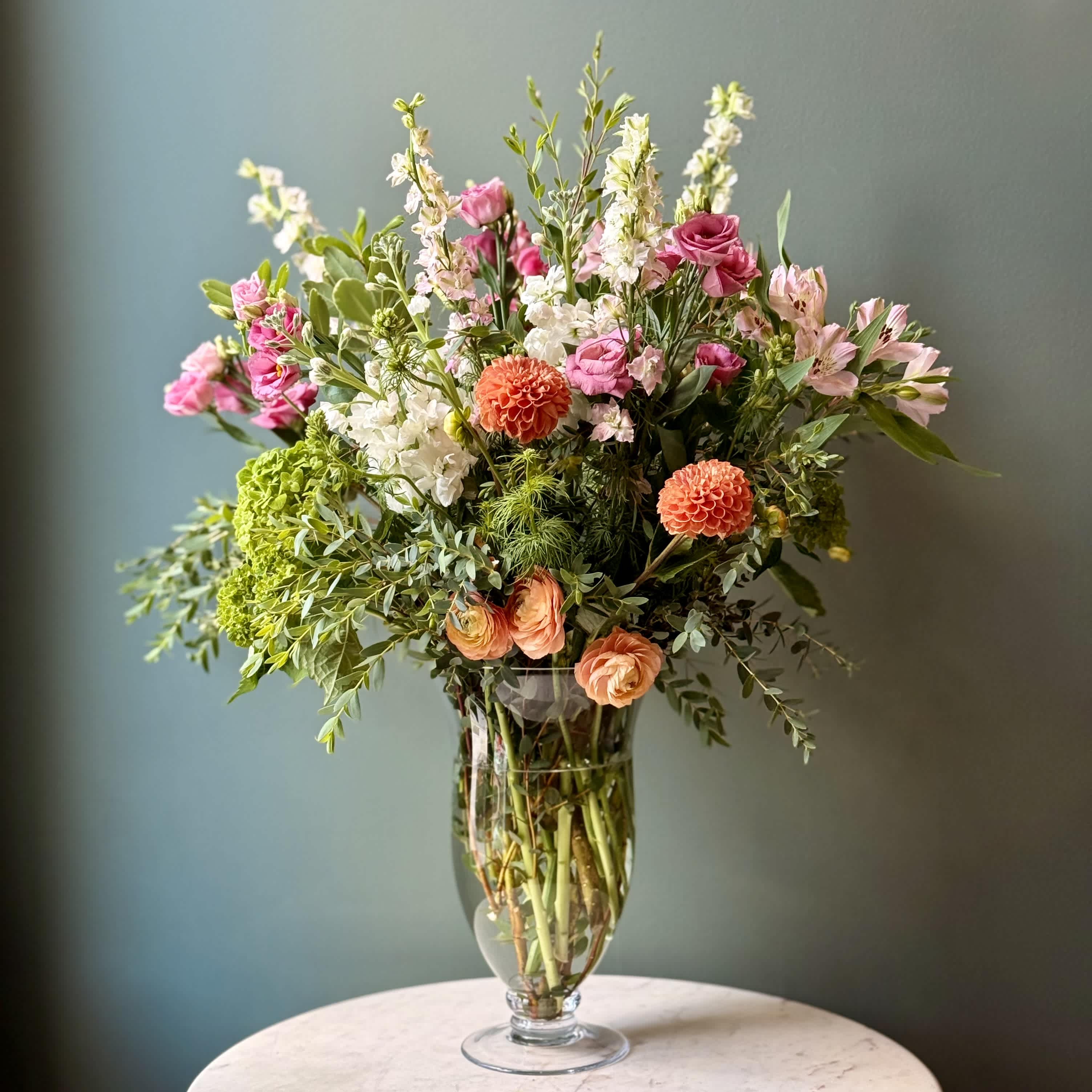 Mixed bouquet of pink, white, and orange flowers in a clear glass vase
