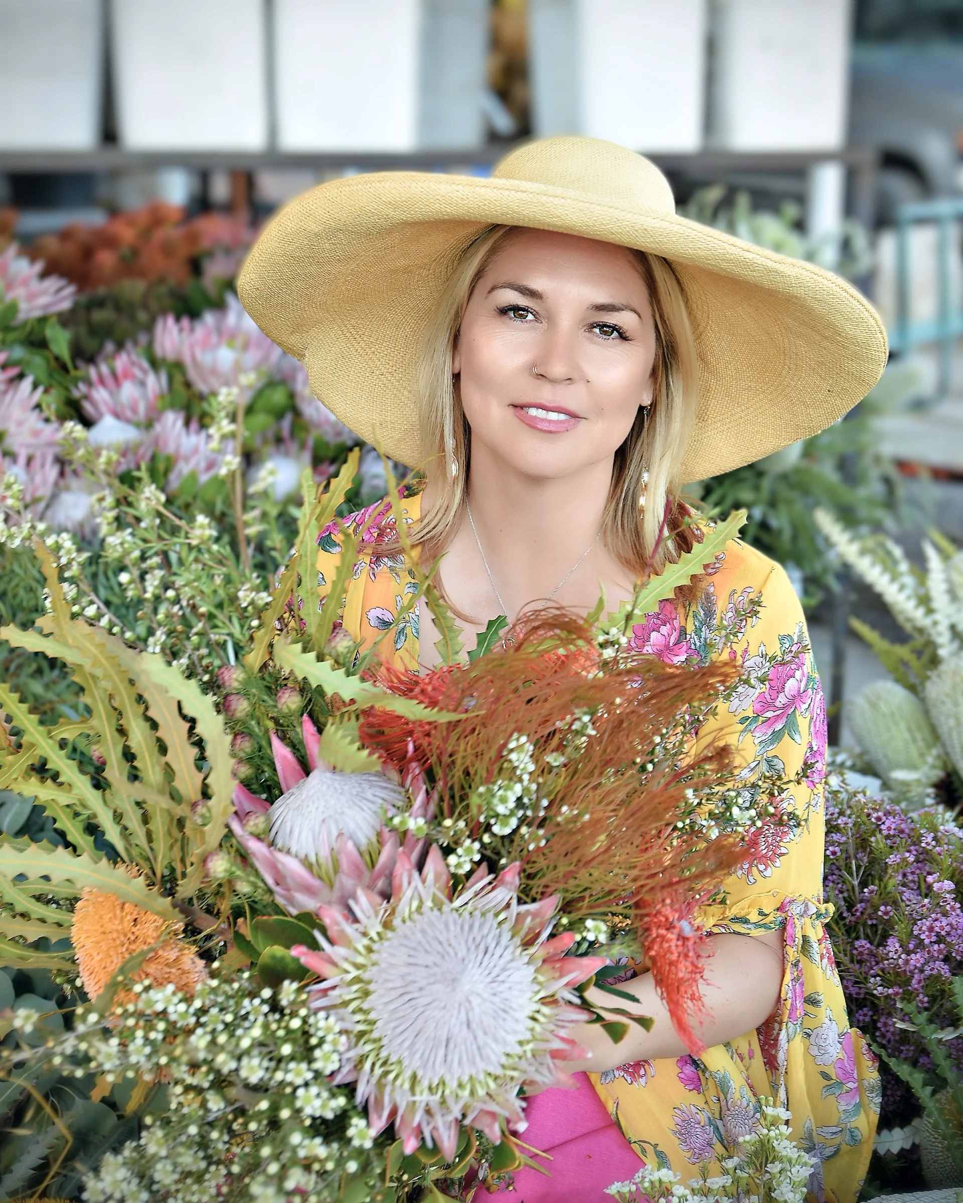 Woman in a wide-brim hat holding a colorful bouquet in a flower shop