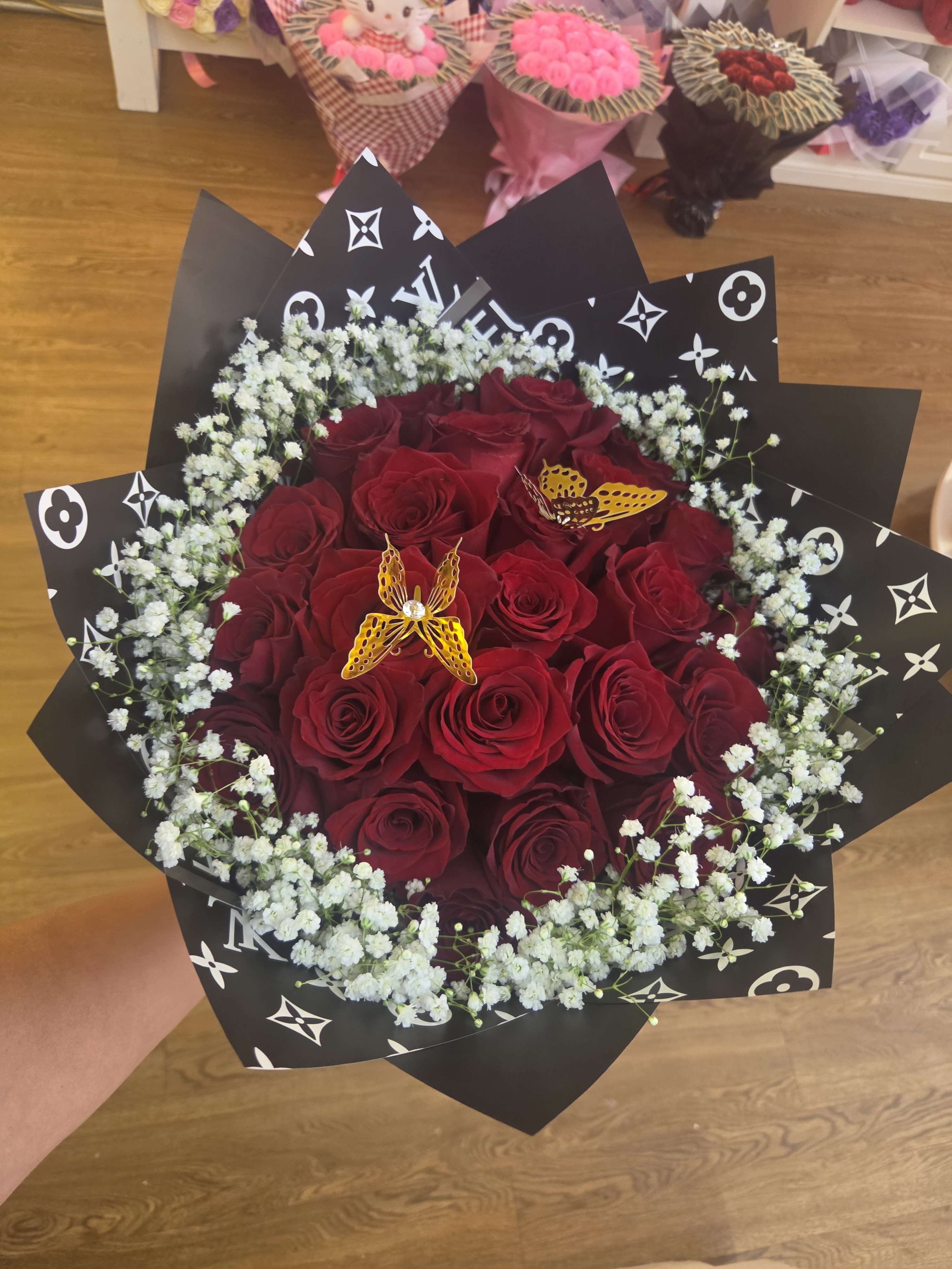 Bouquet of red roses with white baby's breath in black patterned wrap