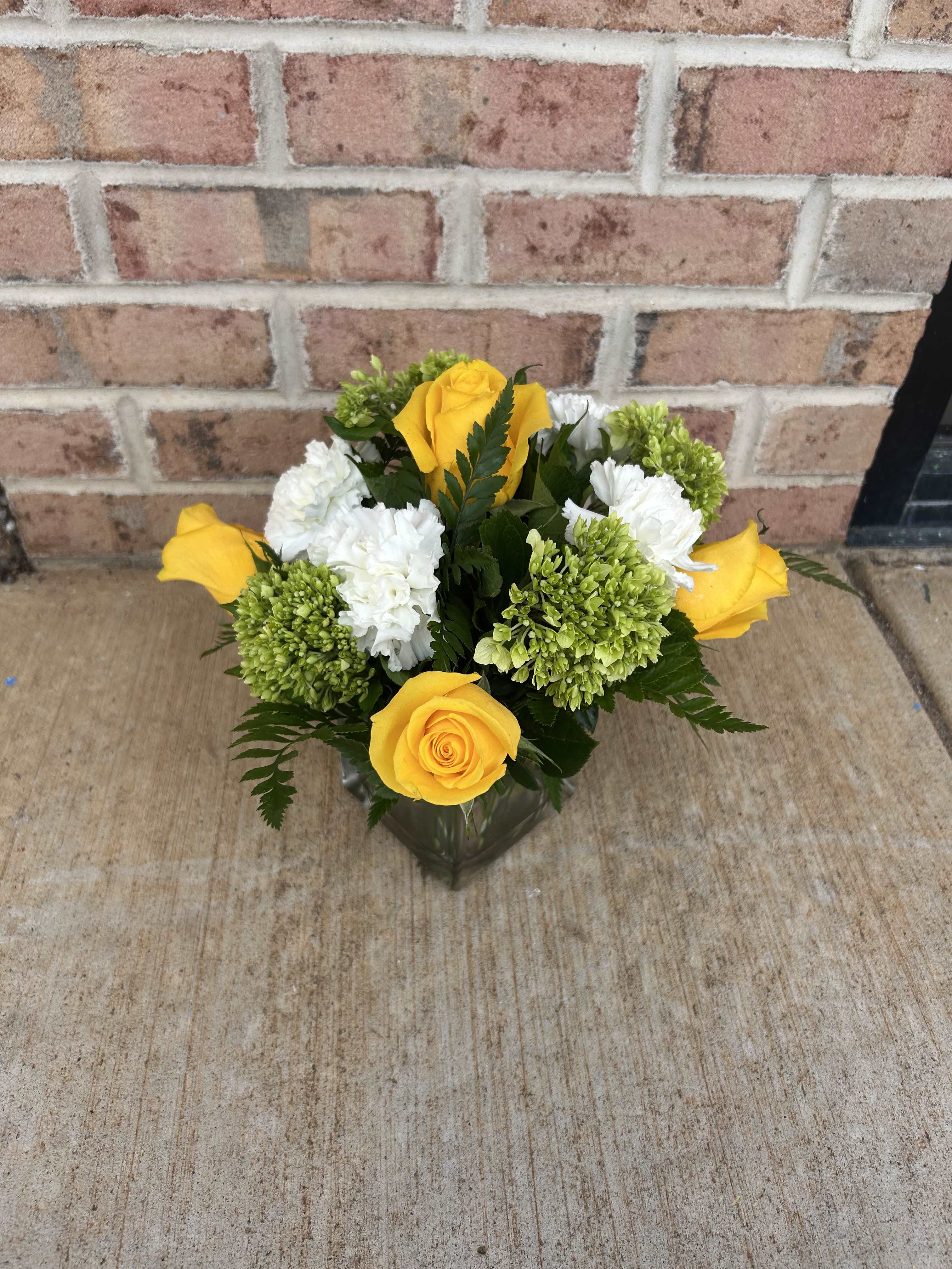 Yellow roses and white carnations in a glass vase