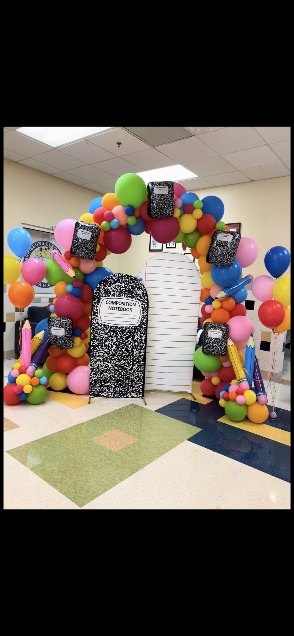 Colorful balloon arch with notebook cutouts and oversized pencils